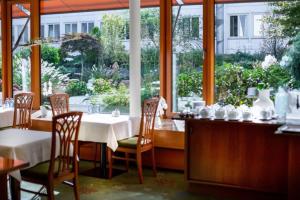 ein Restaurant mit Tischen und Stühlen und einem großen Fenster in der Unterkunft Kronenhotel in Stuttgart