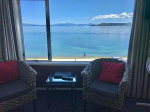 a room with two chairs and a view of the water at Tui Oaks Motel in Taupo