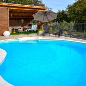 una grande piscina blu con ombrellone di Logis de La Bénétière a Treize-Vents