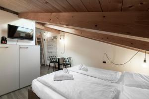 a bedroom with a large white bed and a table at Stay COOPER l Goethe Guesthouse in Bolzano