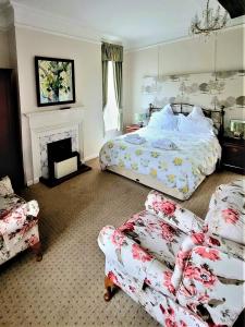 a bedroom with a bed and two chairs and a fireplace at Mangreen Country House in Norwich