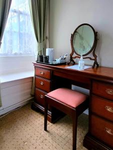 a bathroom with a vanity with a mirror and a stool at Mangreen Country House in Norwich