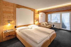 a bedroom with a large bed and a chair at Hotel Antika in Zermatt