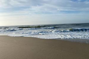 a sandy beach with the ocean and waves at Exclusives Apartment im Herzen von Westerland in Westerland (Sylt)