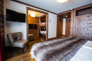 1 dormitorio con 1 cama, TV y silla en Hôtel Champs Fleuris Morzine, en Morzine