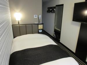 una piccola camera con letto e TV a schermo piatto di APA Hotel Utsunomiya-Ekimae a Utsunomiya