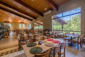 une salle à manger avec des tables et des chaises ainsi qu'une grande fenêtre dans l'établissement Rio Quente Resorts - Hotel Luupi, à Rio Quente