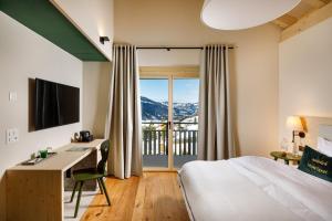 a hotel room with a bed and a desk and a balcony at Hotel Sport Klosters in Klosters