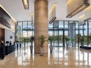 un hall avec des plantes en pot dans un bâtiment dans l'établissement Novotel Citygate Hong Kong, à Hong Kong