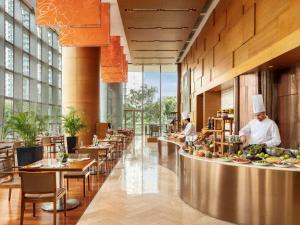 un restaurant avec des chefs préparant vos repas dans une cafétéria dans l'établissement Novotel Citygate Hong Kong, à Hong Kong