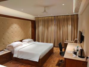 um quarto de hotel com uma cama grande e uma secretária em White Lotus Hotel em Udupi