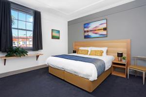 A bed or beds in a room at Meridian Hotel Hurstville