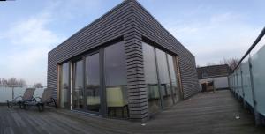 une maison avec des portes en verre sur une terrasse dans l'établissement Hotel Insel Pension, à Niebüll