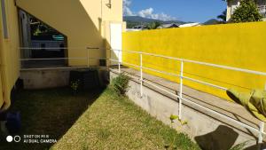 un mur jaune avec une clôture à côté d'une cour dans l'établissement LE SHANTI, à Saint-Pierre