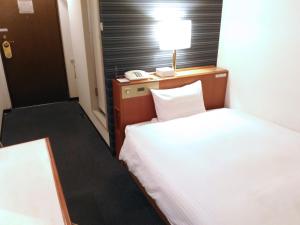 ein Hotelzimmer mit einem Bett, einer Lampe und einem Telefon in der Unterkunft Smile Hotel Towada in Towada