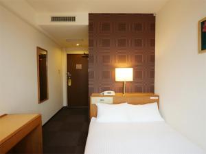 1 dormitorio con cama, escritorio y lámpara en Smile Hotel Towada, en Towada