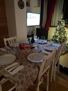 una mesa de comedor con un árbol de Navidad en el fondo en Casa Romeo, en San Vito di Cadore