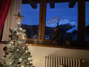 un árbol de Navidad frente a una ventana con una montaña en Casa Romeo, en San Vito di Cadore