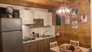 cocina con nevera, mesa y lámpara de araña en Casa Romeo, en San Vito di Cadore