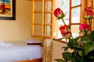 1 dormitorio con 1 cama y una planta con rosas en Tumy house B&B, en Ollantaytambo