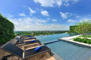 una piscina de borde infinito con tumbonas y vistas a la ciudad en Centre Point Hotel Terminal21 Korat, en Nakhon Ratchasima