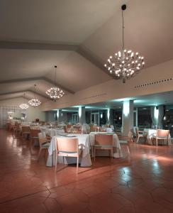 een restaurant met witte tafels en stoelen en kroonluchters bij Parador de Málaga Golf in Málaga