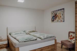 un letto in una stanza con una sedia e un quadro di Peter Lamster Top3 a Frauenkirchen