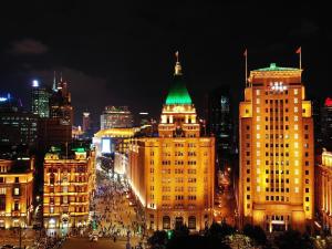 uma cidade iluminada à noite com um telhado verde em Fairmont Peace Hotel on the Bund em Xangai