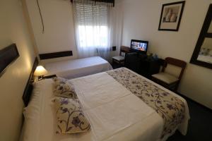 a hotel room with two beds and a television at Hotel Arona in Villa Carlos Paz