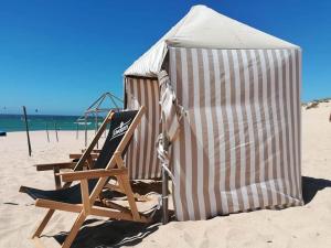 2 sillas de playa y 1 sombrilla en la playa en Furnaka Eco Village, en Lourinhã