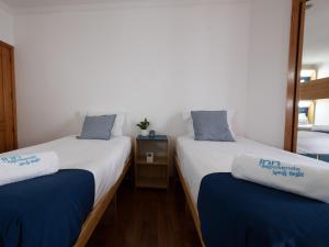 two twin beds with blue and white towels on them at InnEsposende Sports Hostel in Esposende