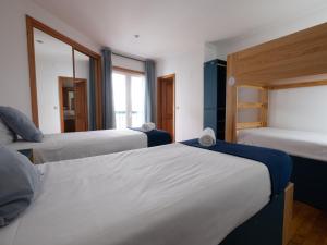 a bedroom with three beds and a window at InnEsposende Sports Hostel in Esposende