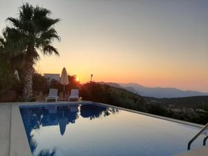 einen Pool mit Sonnenuntergang im Hintergrund in der Unterkunft Villa Emilie Kas in Kaş