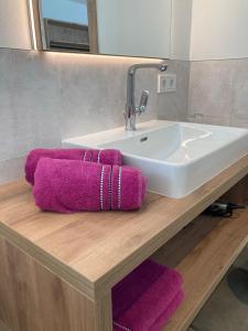 a bathroom sink with purple towels on a wooden counter at Appartements Blumenwiese in Ramsau am Dachstein