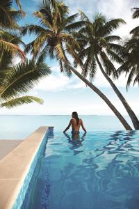 una donna in piedi in una piscina vicino a una palma di Little Polynesian Resort a Rarotonga