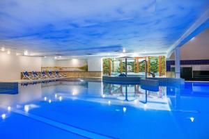 - une grande piscine avec des chaises bleues dans une maison dans l'établissement Hotel Verde Montana Wellness & Spa, à Kudowa-Zdrój