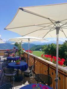 una terraza con mesas, sillas y sombrilla en Hotel & Gasthof zum Hirschen, en San Genesio Atesino