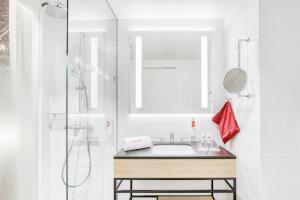 La salle de bains blanche est pourvue d'un lavabo et d'une douche. dans l'établissement IntercityHotel Wiesbaden, à Wiesbaden