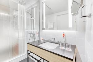 La salle de bains blanche est pourvue d'un lavabo et d'une douche. dans l'établissement IntercityHotel Wiesbaden, à Wiesbaden