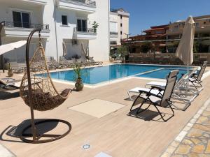 un patio con sedie e altalena accanto alla piscina di METROPOLIS a Ulcinj