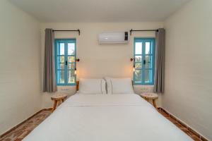 uma cama branca num quarto com duas janelas em Yonca Lodge em Fethiye