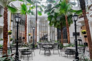 ein Restaurant mit Tischen, Stühlen und Palmen in der Unterkunft Hotel Savoy Homann in Bandung