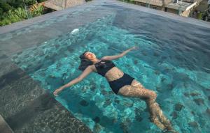 Eine Frau in einem Schwimmbad mit Frisbee. in der Unterkunft Kayangan Boutique Hotel in Sanur