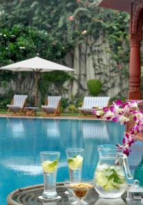 een tafel met drankjes en bloemen naast een zwembad bij The Grand Imperial - Heritage Hotel in Agra