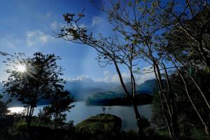 una vista su un lago con il sole nel cielo di Ottway Hills Near Mattupetty Dam a Munnar