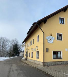 um edifício amarelo na berma de uma estrada em Gasthof zum Kirchenwirt em Kirchdorf am Inn