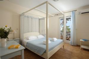 - une chambre avec un lit à baldaquin blanc et un balcon dans l'établissement Aeolos Hotel, à Koufonisia