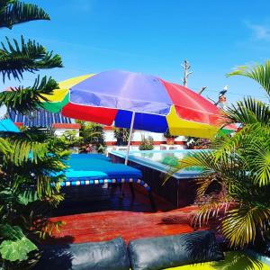 einen bunten Regenschirm über einer Bank neben einem Pool in der Unterkunft Hotel Kevin in San Felipe de Puerto Plata