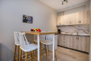 una cocina con taburetes blancos y una mesa con fruta. en ALDEBARAN HOMES, en Limenaria