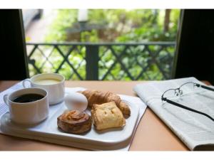 een bord gebak en twee kopjes koffie op een tafel bij R&B Hotel Kumagaya Ekimae - Vacation STAY 14849v in Kumagaya